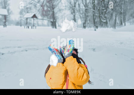 little girl in yellow jacket with throws snow winter Stock Photo