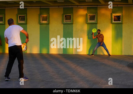 Two young men playing with a paddle and rubber ball AKA Matkot on the beach. Photographed on the beach, Tel Aviv, Israel at sunset Stock Photo