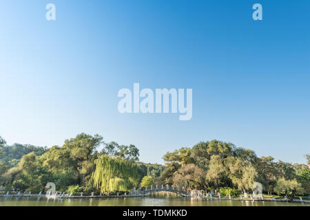 Autumn China Fushun early morning park river bank willow stone bridge cruise ship Stock Photo