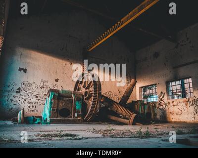 Giant old rusty gears in old warehouse random writing on the wall Stock Photo