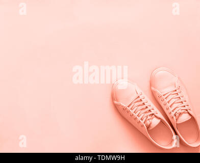 Pink leather sneakers on peach or pink background. Pair of pink sport shoes or sneakers with copy space for text or design. Overhead shot of new pink sneakers,monochrome.Top view or flat lay Stock Photo