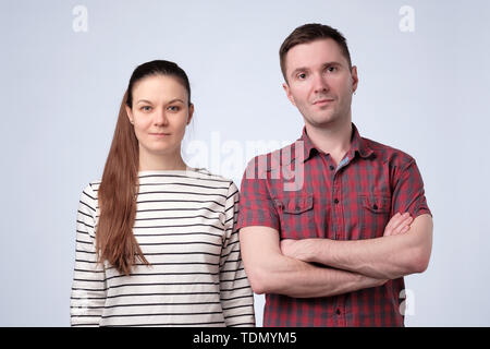 Serious european couple on gray studio wall standing together. Stock Photo