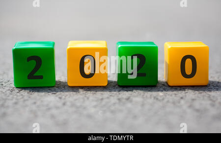 Plastic cubes with 2020 text placed on grey asphalt on the sun Stock Photo