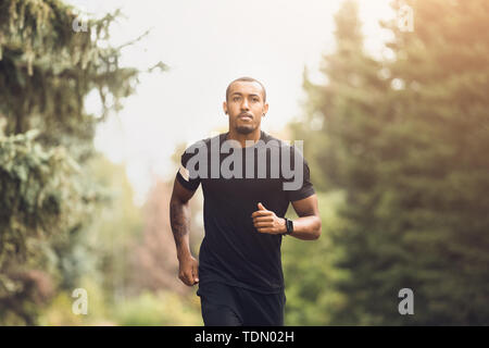 Fit African-American Guy Running In The Park Stock Photo