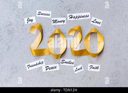 Best new year wishes with gold ribbon 2020 text on grey wall Stock Photo