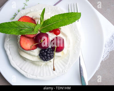 Meringues Pavlova cakes with fresh berry, mint leaf on concrete background, top view Stock Photo