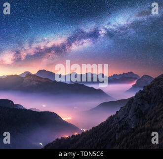 Milky Way over mountains in fog at night in summer. Landscape Stock Photo