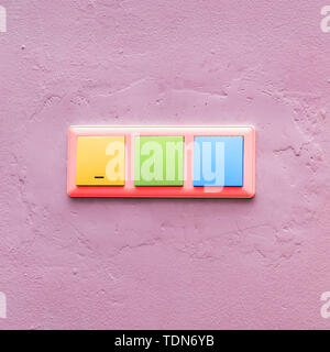 Multi-colored light switches on a pink wall. Fashionable colorful electrical switch. Creative style. art Stock Photo