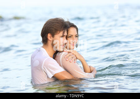 Dressed happy couple looking away bathing on the beach on summer vacation Stock Photo