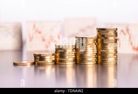 Rising stacks of coins and charts with stock prices in the background Stock Photo