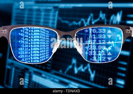 Glasses with financial data and monitor in the background Stock Photo