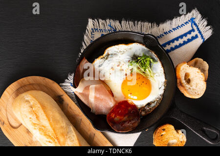 Food Breakfast concept fried egg in skillet iron pan with flax sprouts and bacon with copy space Stock Photo