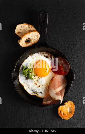 Food Breakfast concept fried egg in skillet iron pan with flax sprouts and bacon with copy space