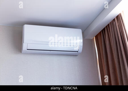 Small air conditioning on the wall inside room in apartment, switched off. Interior in calm beige tones. Stock Photo