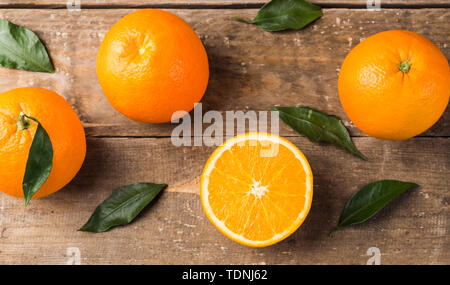 Fresh oranges and leaves on wooden board background Stock Photo