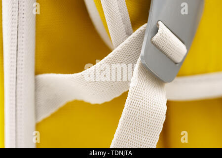 Locked gray metal buckle on white strap on yellow sports backpack Stock Photo