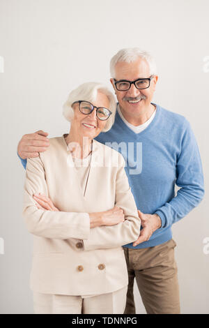 Happy senior affectionate couple with toothy smiles over white background standing in front of camera Stock Photo