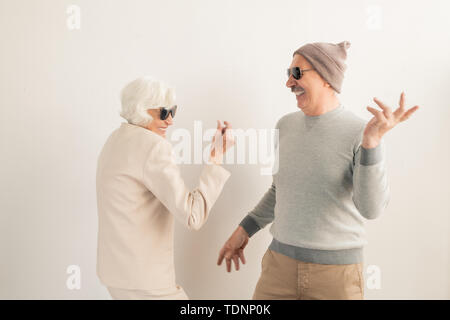 Happy casual senior couple in sunglasses having fun and dancing in isolation over white background Stock Photo