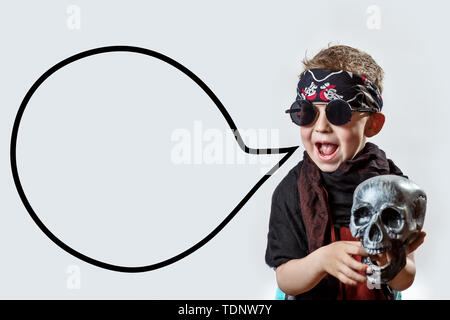 boy rocker in black glasses, scarf, bandana and with a skull in his hands on a light background Stock Photo