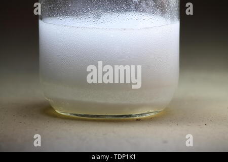 Closeup of a vinegar and baking soda reaction happening in the bottom of a glass jar; generating a lot of fizz Stock Photo