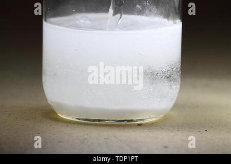Closeup of a vinegar and baking soda reaction happening in the bottom of a glass jar Stock Photo