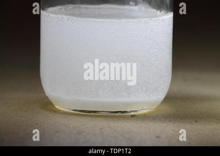 Closeup of a vinegar and baking soda reaction happening in the bottom of a glass jar; solution cloudy Stock Photo