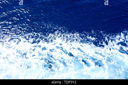 Rippled sea water in ink blue color tone and white sea foam, top view. Abstract water background Stock Photo
