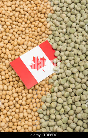 Canadian flag with dried soy beans and dried peas. Canadian producers have faced obstacles obstacles of farm goods entering China. Stock Photo