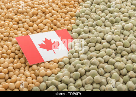 Canadian flag with dried soy beans and dried peas. Canadian producers have faced obstacles obstacles of farm goods entering China. Stock Photo