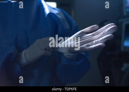 Female surgeon with surgical gloves in operation room Stock Photo