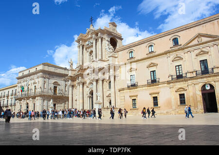 Syracuse, Sicily, Italy - Apr 10th 2019: Amazing view of Syracuse Cathedral on Piazza Duomo Square in Ortigia Island. Photographed with tourists walking on the square. Beautiful tourist site. Stock Photo