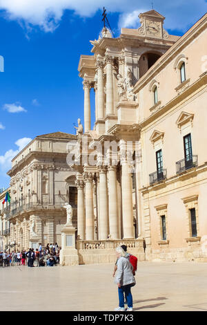 Syracuse, Sicily, Italy - Apr 10th 2019: Tourists on Piazza Duomo Square in Ortygia Island. Dominant of the historical center is Baroque Syracuse Cathedral. Vermexio Palace, town hall, in background.