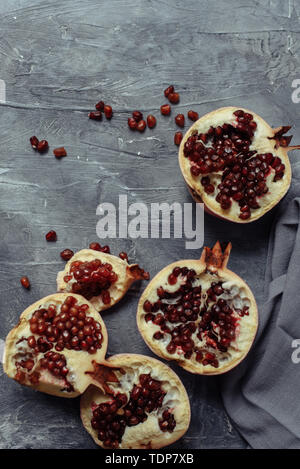 Several ripe pomegranates on a gray grunge concrete background. Grenades with large red grains lie on the concrete pavement. Top view and place for te Stock Photo