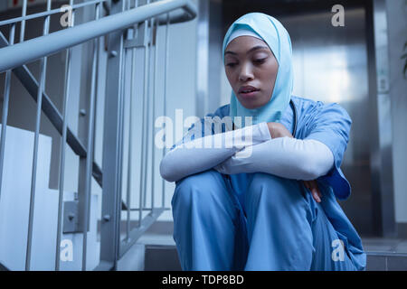 Nurse in hijab sitting on stairs at hospital Stock Photo