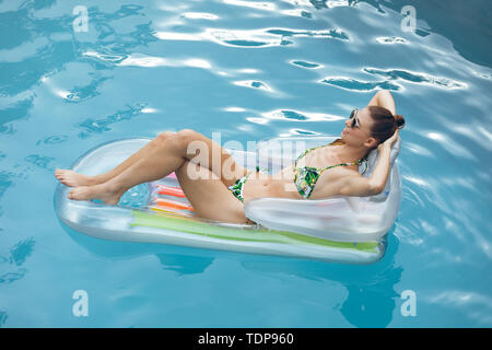 Woman in bikini relaxing on a inflatable tube in swimming pool