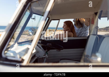 Happy young couple looking away near camper van at beach Stock Photo