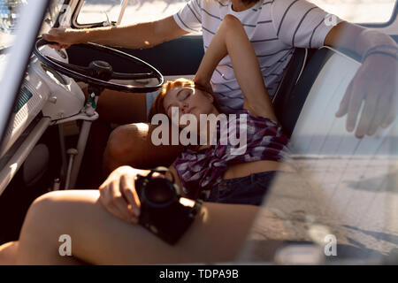 Beautiful woman relaxing on man lap in front seat of camper van at beach Stock Photo