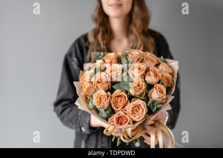 Flowers coffee color, cappuccino roses with eucalyptus. Small Beautiful bouquets in woman hand. Floral shop concept. Flowers delivery Stock Photo