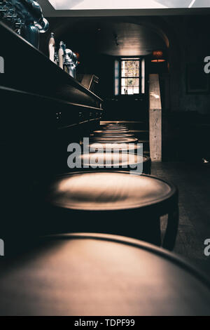 Dramatic shot of wooden stools in a row at the bar of an old English Pub in the North of England. Stock Photo