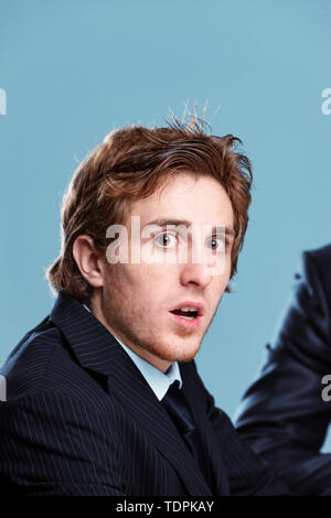 Shocked businessman turning to gawp at the camera with open mouth and wide eyes as he sits in a meeting with a colleague or boss Stock Photo