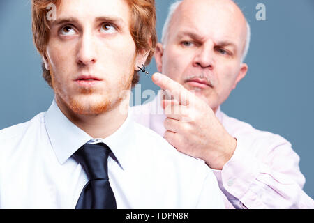 Senior businessman pointing to a bored looking workers earring in a concept of modern trendy dress code versus old-fashioned classicism Stock Photo