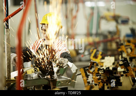 On a welding line, the only female welder is welding small pieces of the body. Stock Photo