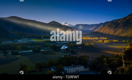 In the early morning of autumn, the sun shines on the poplar treetops of the Xindu Bridge, and Gongga in the distance is shrouded by flowing clouds. Stock Photo