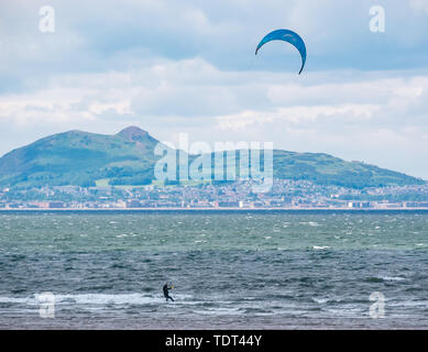 Longniddry Bents, Firth of Forth, Scotland, United Kingdom, 18th June 2019. UK Weather: Kite surfers have ideal conditions at low tide with a strong wind and sunshine in the choppy Firth of Forth looking towards the distinctive skyline of Edinburgh across the bay Stock Photo