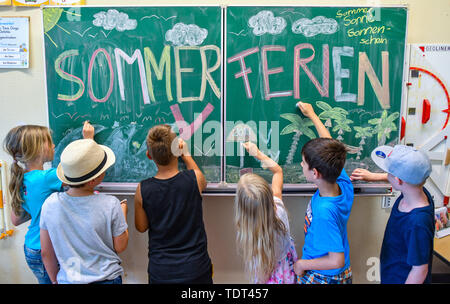 18 June 2019, Brandenburg, Booßen: ILLUSTRATION: The pupils (l-r) Nele, Ben, Tommes, Johanna, Domenik and Arijen from class 2A of the elementary school 'Am Mühlenfließ' paint in their classroom on a blackboard with the inscription 'Sommerferien' (picture taken). On 19.06.2019 is the last school day in Berlin and Brandenburg. The summer holidays run from 20 June to 02 August 2019. Photo: Patrick Pleul/dpa-Zentralbild/ZB Stock Photo