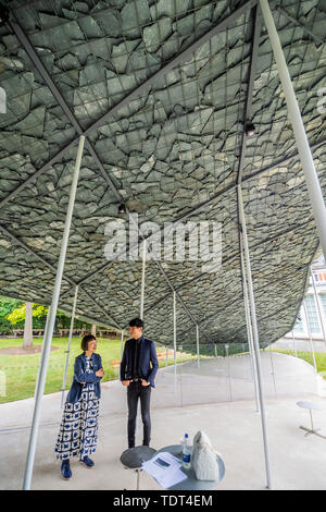 London, UK. 18th June, 2019. Serpentine Pavilion 2019, designed by Japanese architect Junya Ishigami (pictured). His design takes inspiration from roofs and is made by arranging slates to create a single canopy roof that appears to emerge from the ground of the surrounding Park. Within, the interior of the Pavilion is an enclosed cave-like space, a refuge for contemplation. It articulates his ‘free space’ philosophy in which he seeks harmony between man-made structures and those that already exist in nature. Open to the public 21 June – 6 October 2019. Credit: Guy Bell/Alamy Live News Stock Photo