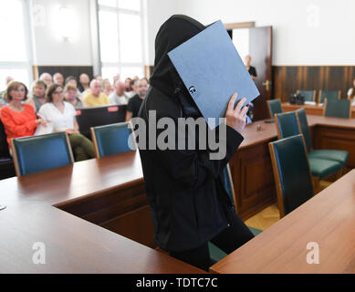 19 June 2019, Hessen, Darmstadt: A 47-year-old woman takes a seat in the courtroom of the Regional Court with a file in front of her face to pronounce her sentence. The father was sentenced to life imprisonment for the murder of his two children and the mother to 12 years for aiding and abetting the murder. According to the prosecution, the insolvent dentist couple killed and stabbed the girl and her brother together on the night of August 31, 2018. According to the report, the parents set fire to the house and unsuccessfully tried to kill themselves with car exhaust fumes. Photo: Arne Dedert/ Stock Photo