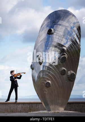 Viktor Seifert, 12, from St Mary's Music School in Edinburgh, plays the Orca Driftwood Viola alongside the giant mussel shell sculpture at Musselburgh, East Lothian, ahead of his performance at the Royal Academy of Music in London on July 18th 2019, in the 'Dance For The Sea' event which supports the work of the Marine Conservation Society. Stock Photo