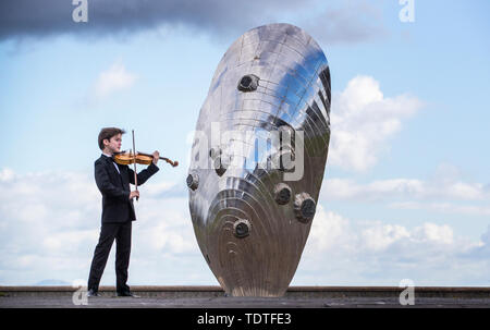 Viktor Seifert, 12, from St Mary's Music School in Edinburgh, plays the Orca Driftwood Viola alongside the giant mussel shell sculpture at Musselburgh, East Lothian, ahead of his performance at the Royal Academy of Music in London on July 18th 2019, in the 'Dance For The Sea' event which supports the work of the Marine Conservation Society. Stock Photo