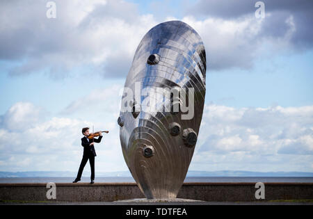 Viktor Seifert, 12, from St Mary's Music School in Edinburgh, plays the Orca Driftwood Viola alongside the giant mussel shell sculpture at Musselburgh, East Lothian, ahead of his performance at the Royal Academy of Music in London on July 18th 2019, in the 'Dance For The Sea' event which supports the work of the Marine Conservation Society. Stock Photo